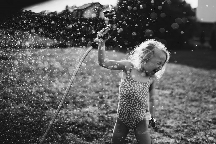 Girl playing with a hose in the sunlight