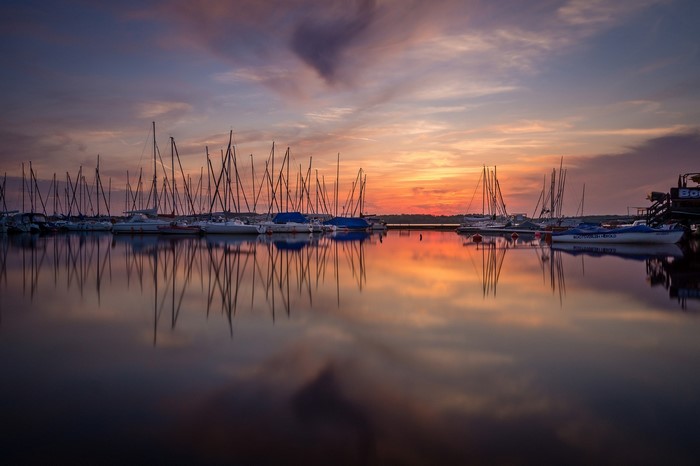 Sailboats docked at sunset with reflections on the water