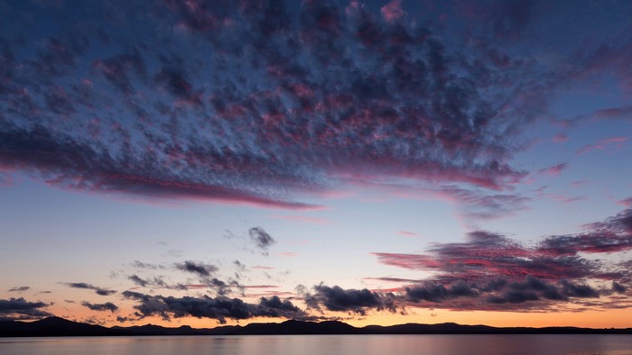 Sunset over a lake with mountains and clouds