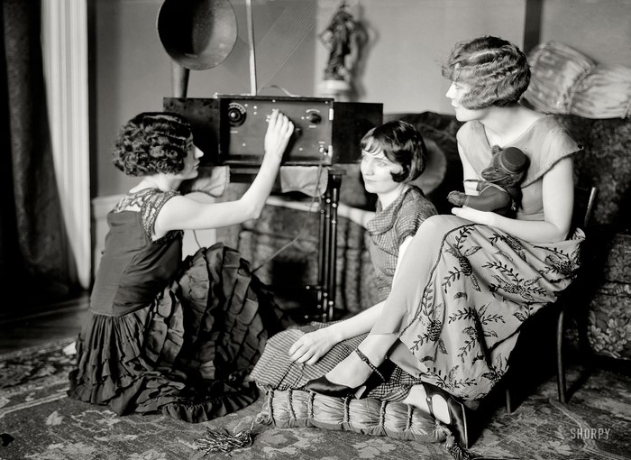 Three women gathered around a radio