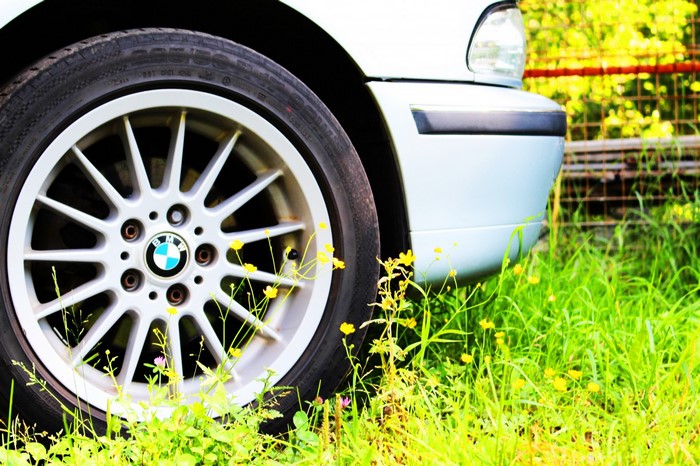 BMW car wheel and bumper in grass with flowers