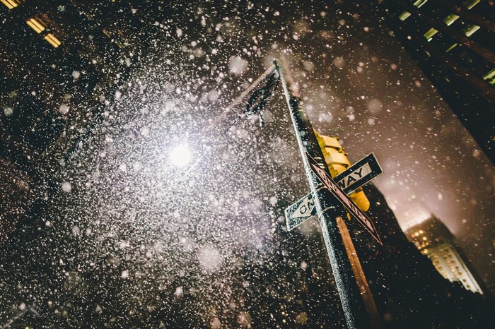 Snow falling on a New York City street at night