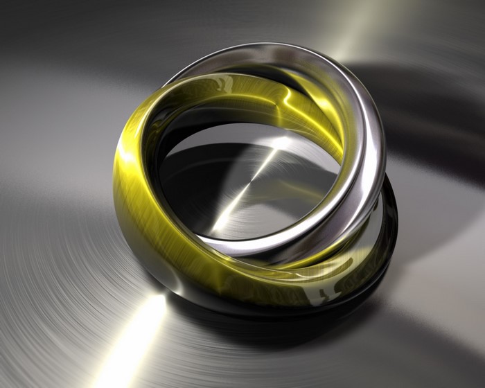 Interlocking gold and silver rings on brushed metal surface