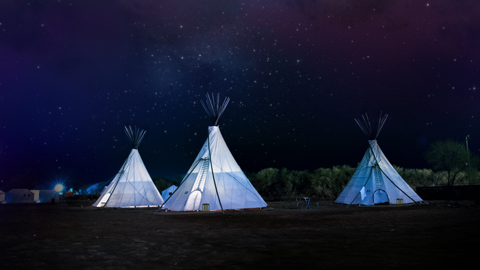 Tipi tents under a starry night sky