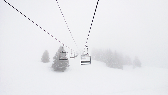 Ski lift in a snowy blizzard with pine trees
