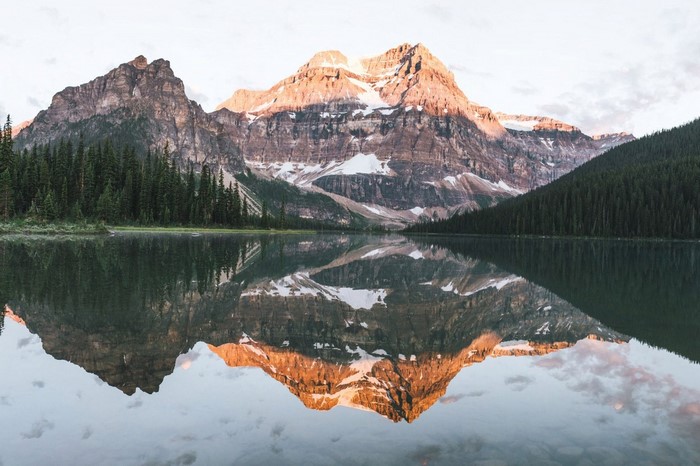 Mountain range reflected in a calm lake with pine forest