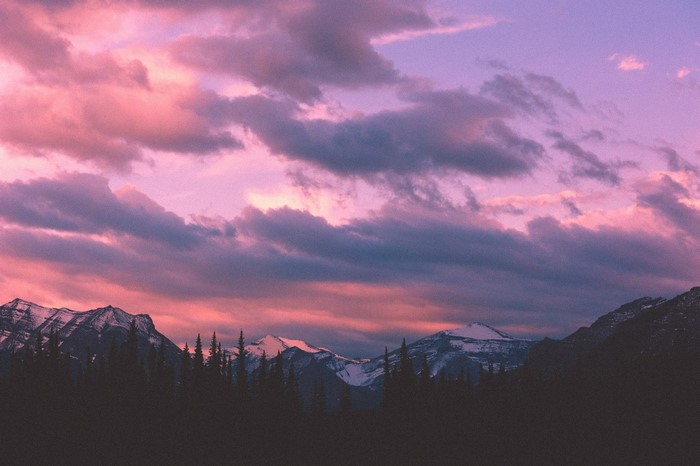Mountains and forest at sunset with pink and purple clouds