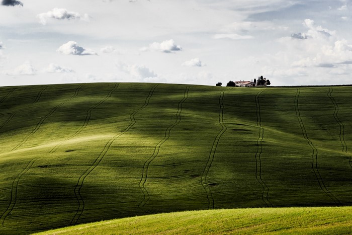 Rolling green hills with a farm on the horizon