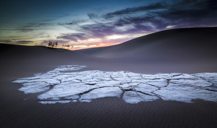 Cracked earth in a desert landscape at sunset
