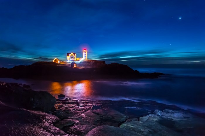 Lighthouse decorated with lights at night by the sea