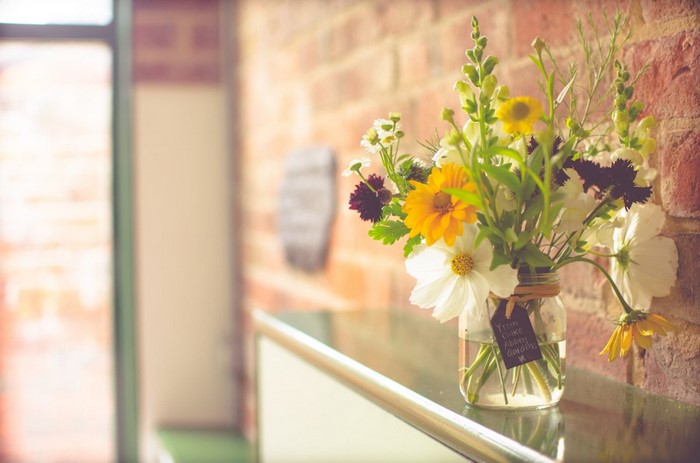 Bright Floral Arrangement in Jar by Brick Wall