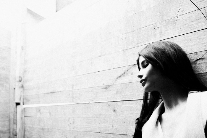 Woman leaning against wooden wall