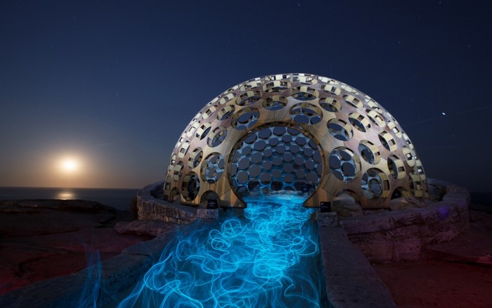 Dome artwork with blue light painting on the coast at night