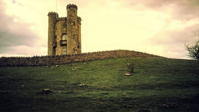 Castle tower on a grassy hill with stone wall
