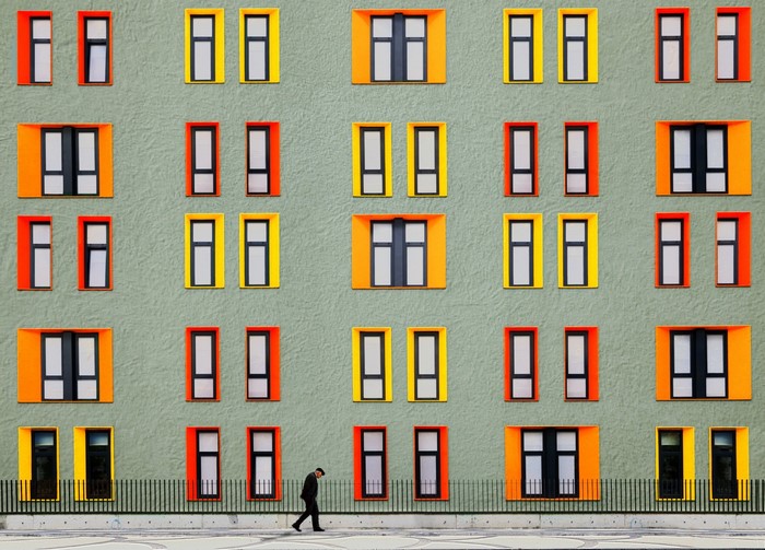 Man walking in front of a colorful modern building facade