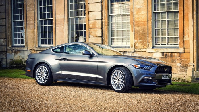Gray Ford Mustang parked in front of a stone building