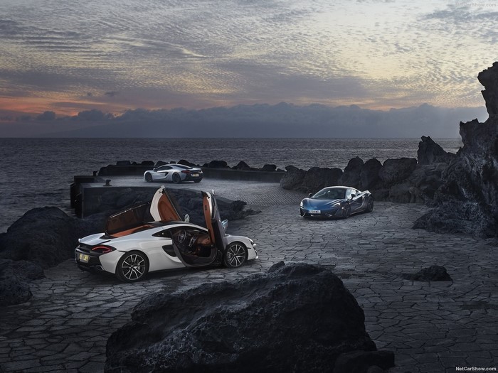 McLaren 570GT cars on rocky coast at dusk