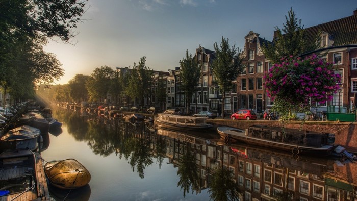 Amsterdam canal with historic buildings and boats at sunrise