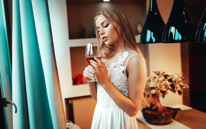 Woman in white dress holding a glass of red wine