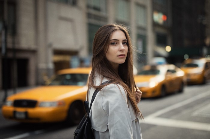 Woman in trench coat on a city street with yellow taxis