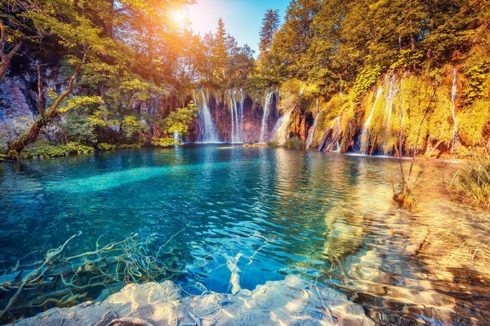 Waterfalls cascading into a clear turquoise lake in autumn