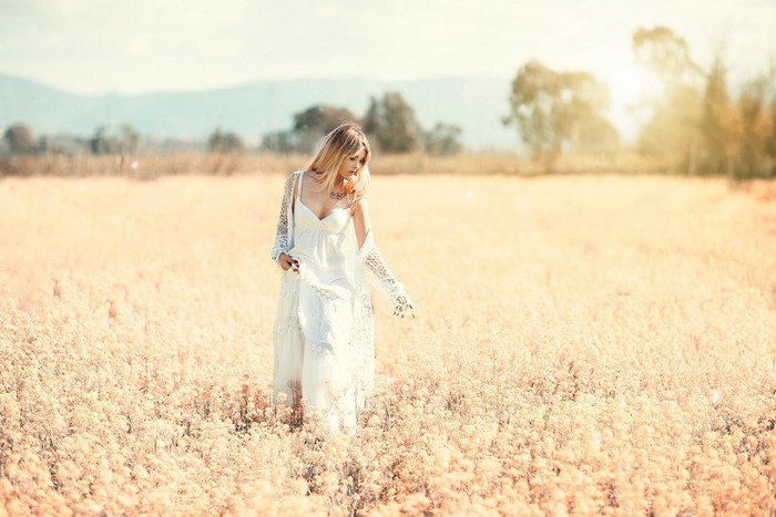 Woman in white dress walking through a field