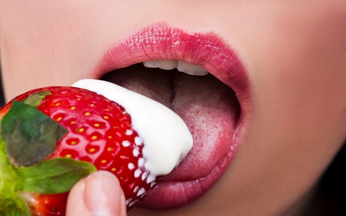 Woman eating a strawberry with cream