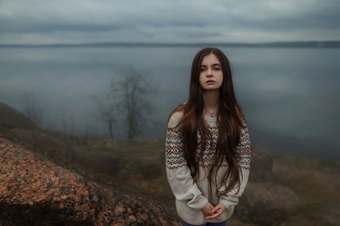 Young woman in a patterned sweater by the water