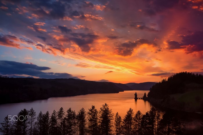 Sunset over a lake with a tower and trees