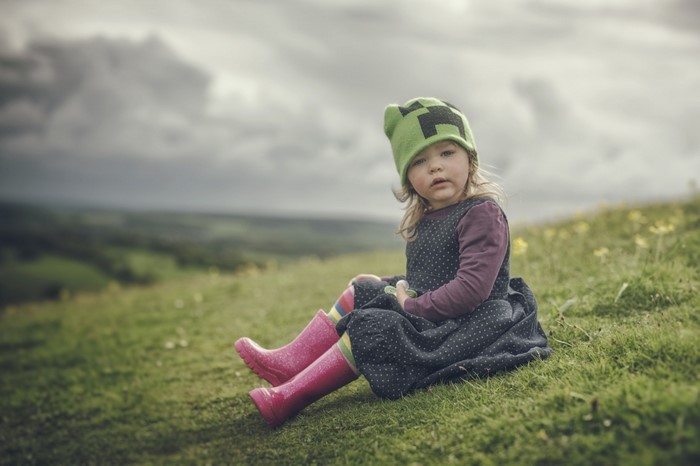 Girl in Creeper hat sitting on a grassy hill