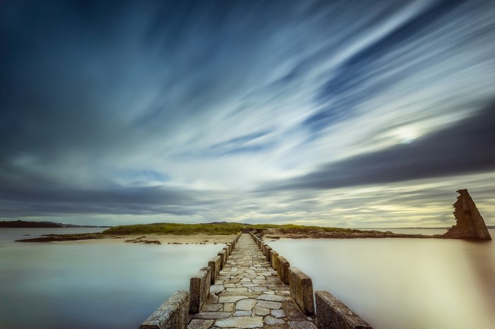 Stone bridge over water with dramatic clouds