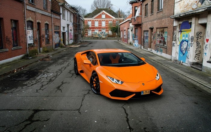 Orange Lamborghini Huracan parked on a street with graffiti