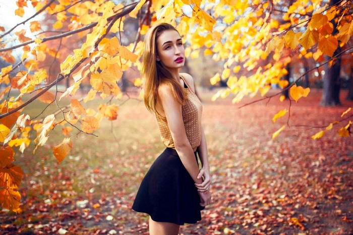 Woman in a golden top and black skirt in autumn park