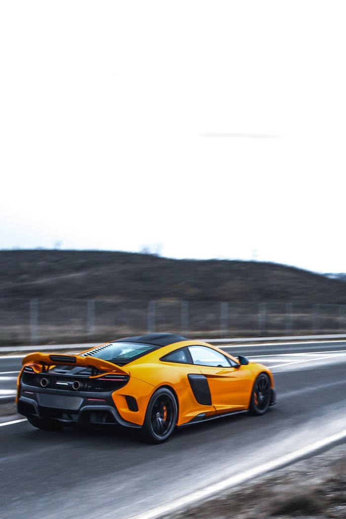 Orange McLaren 675LT driving on a highway