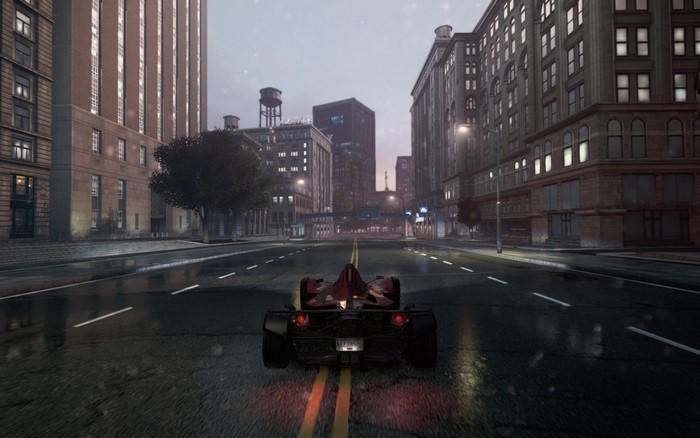 Red race car driving on a wet city street at dusk