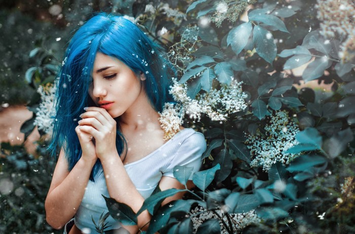 Woman with blue dyed hair among flowers