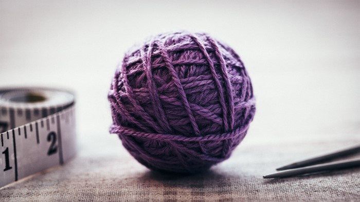 Purple yarn ball with knitting needles and measuring tape