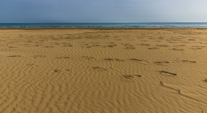 Sandy beach with footprints and the sea horizon