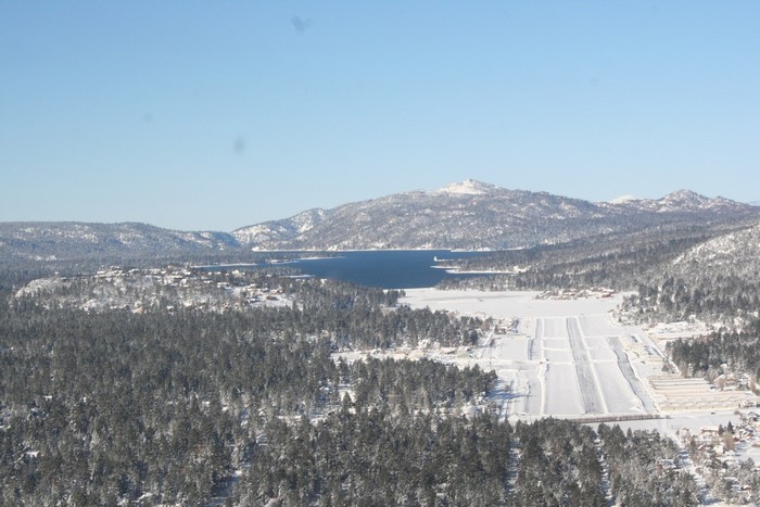 Aerial view of a snow-covered landscape with a lake and mountains