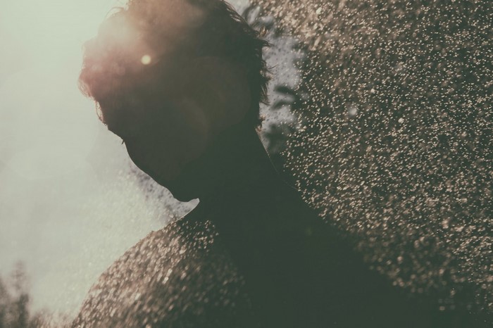 Silhouette of a person in sunlight with water droplets
