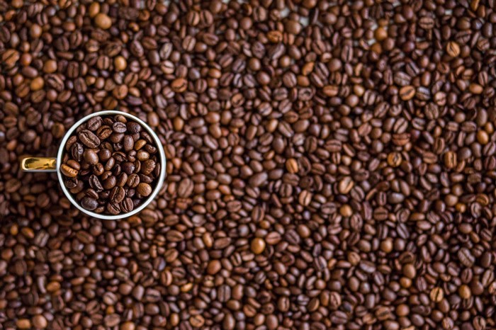 Cup of coffee beans on a bed of coffee beans