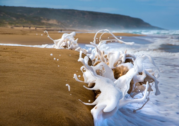 Wave crashing on a sandy beach with foam