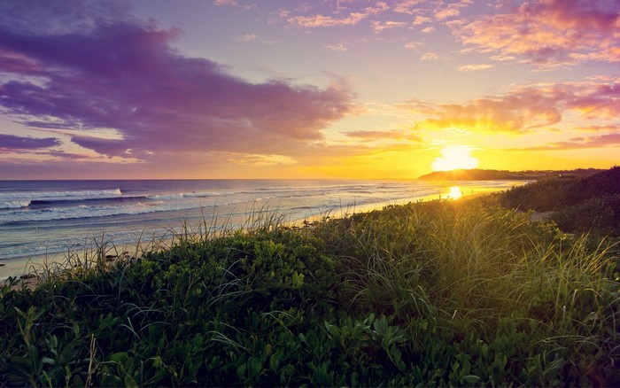 Sunset over the ocean with waves and grass