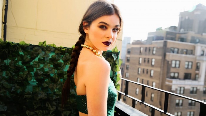 Hailee Steinfeld posing on a balcony with buildings in the background