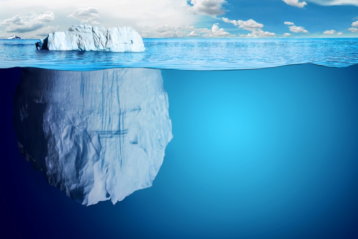 Iceberg floating in the ocean under a cloudy sky