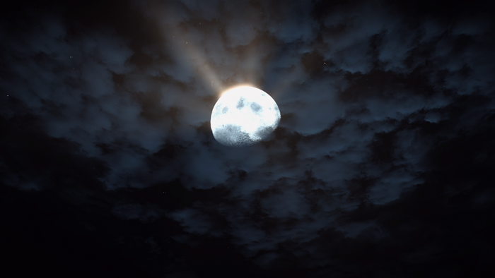 Full moon shining through clouds at night