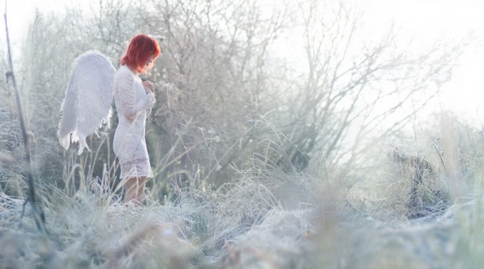 Woman with angel wings in a frosty winter landscape