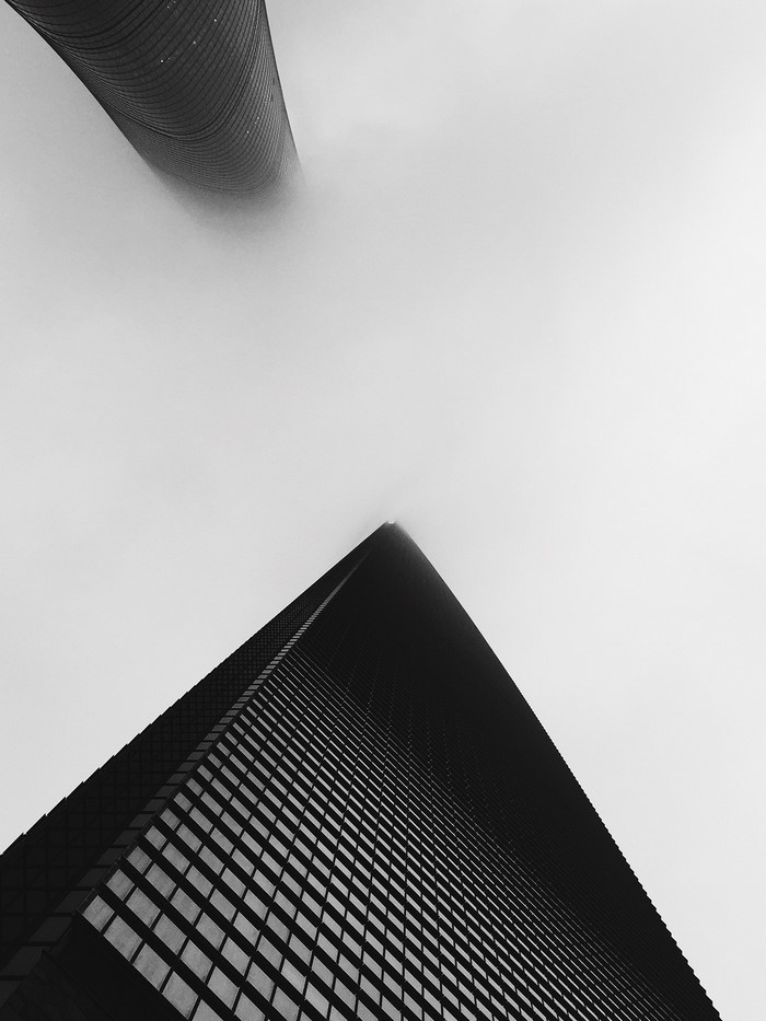 Two skyscrapers shrouded in fog, black and white
