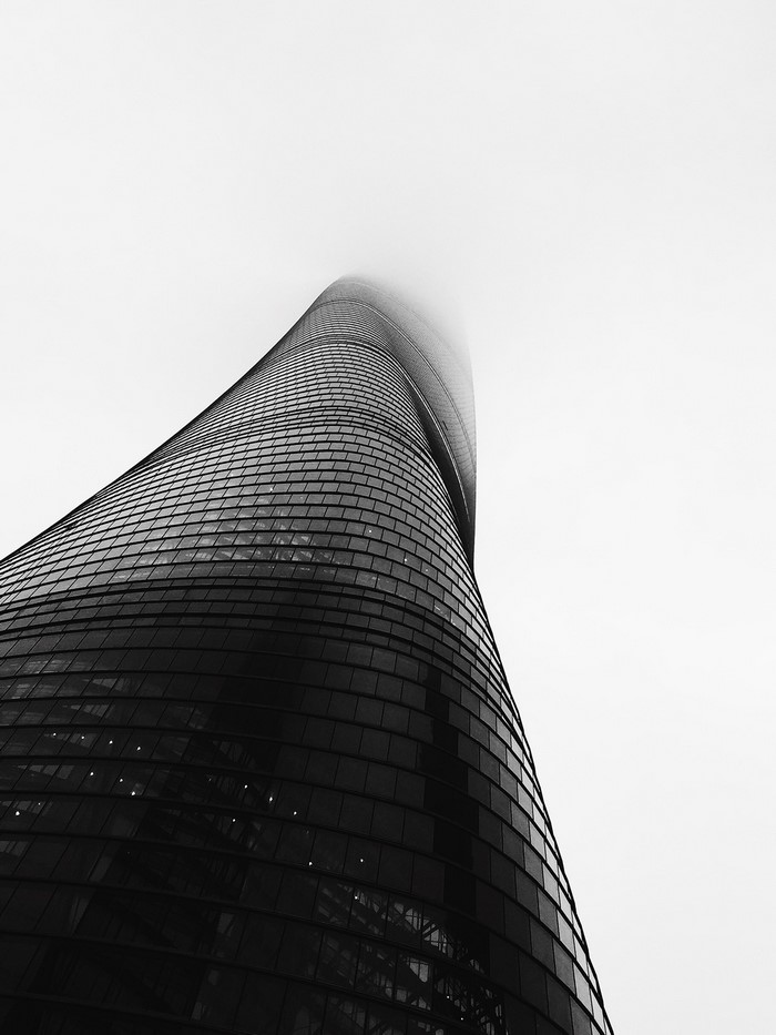 Monochrome view of a modern skyscraper disappearing into the clouds