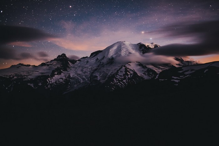 Snow-capped mountains under a starry night sky
